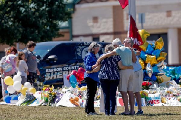 Mourners pay their respects at the a large makeshift memorial in front of Apalachee High School, days after a shooting left two students and two teachers dead in Winder, Georgia.